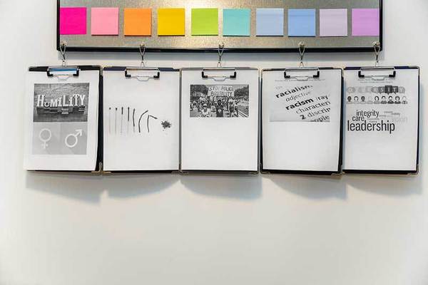 Colorful post it notes and clipboards holding photos of typography about racism, justice, and equality.