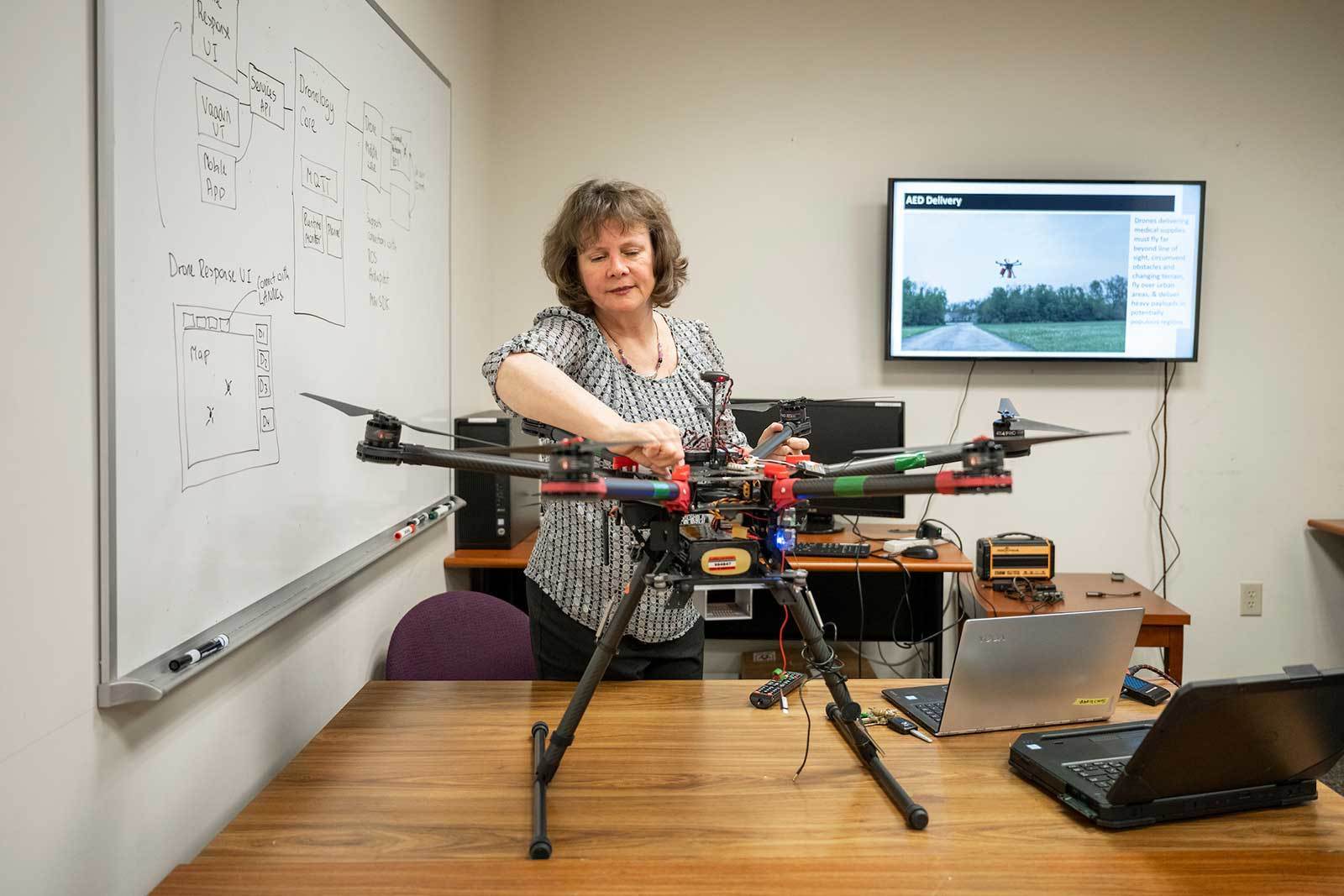 A woman inspects a large drone on a table.